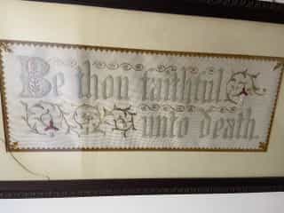 Embroidered sampler reading 'Be thou faithful unto death' — hung on Geoffrey Clayton's wall